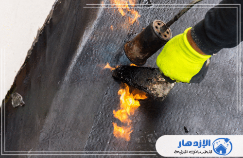 لقطة قريبة لعامل يرتدي قفازات واقية ويقوم بلحم طبقات عزل الأسطح بأقصى درجات الدقة والمهنية. نضمن أعلى معايير الجودة في أم القيوين. للحماية المثلى، شركة الإزدهار 0505587508.