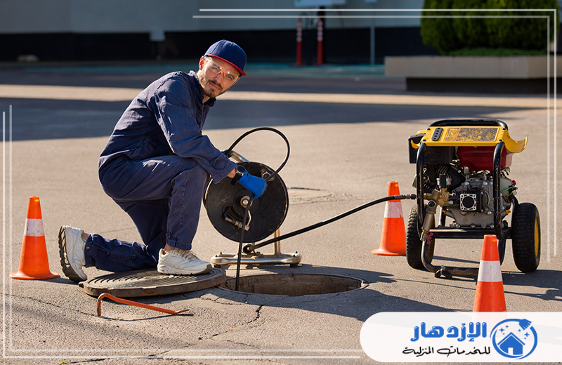 الصرف الصحي في راس الخيمة 0505587508  سباك صرف صحي يرتدي بدلة زرقاء ويقوم بأعمال في نظام المجاري.