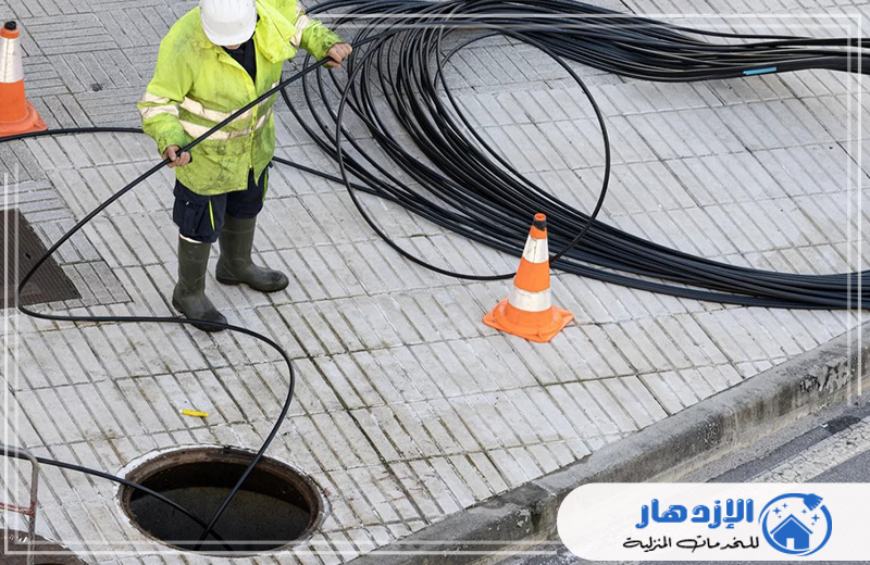 تسليك المجاري في راس الخيمة رجل يرتدي سترة صفراء يعمل على تسليك مجاري في موقع بناء.